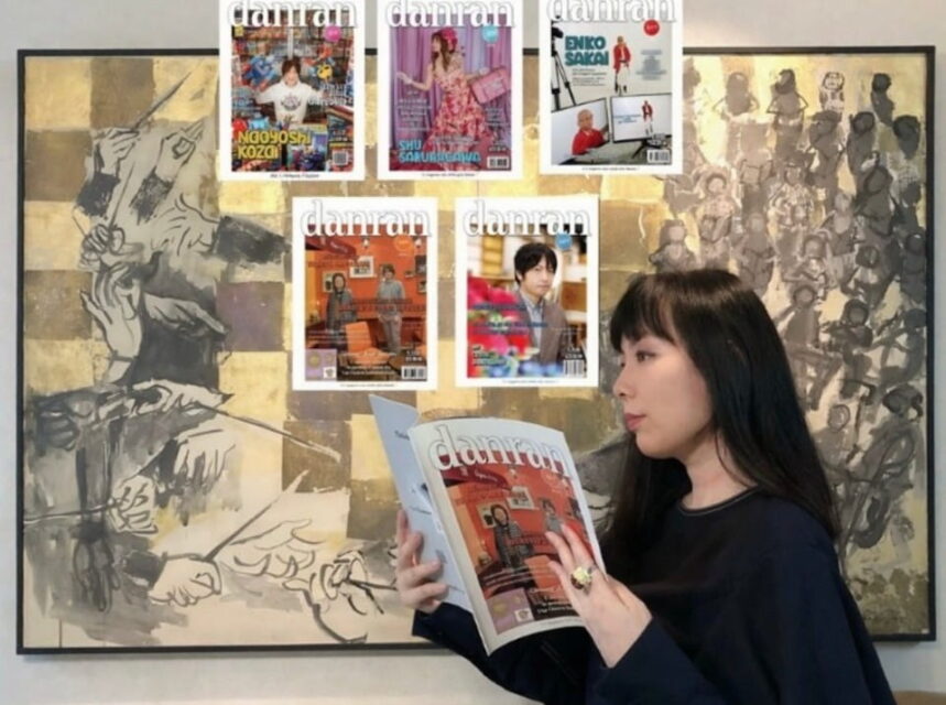 Portrait photographique de Eru Gibson, rédactrice en chef de danran, lisant un numéro de son magazine devant une grande peinture murale d'art contemporain. Plusieurs autres couvertures de danran sont affichées sur le mur derrière elle.