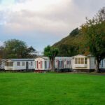 Des mobile homes sur un pré vert avec arbres et colline