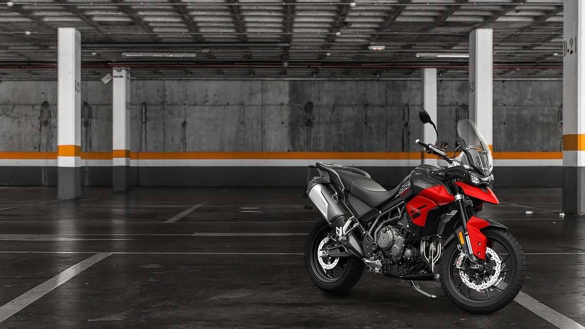 Motocyclette rouge garée seule dans un parking souterrain avec colonnes de béton Motocyclette rouge garée seule dans un parking souterrain avec colonnes de béton