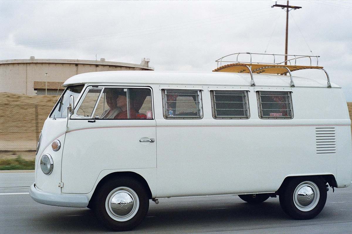 Van blanc vintage avec toit porte-bagages et conducteur visible