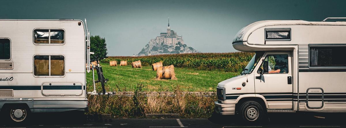Deux camper vans garés devant un champ avec moutons et Mont Saint-Michel